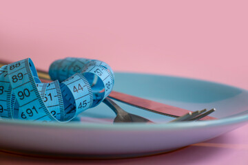 Fork, knife, plate measuring tape on a colored background