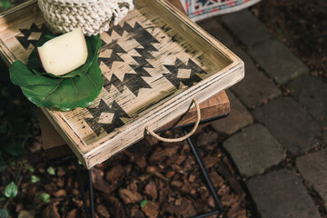 decorative wooden furniture in vintage style, wooden tray with an ornament, piece of cheese on a green leaf