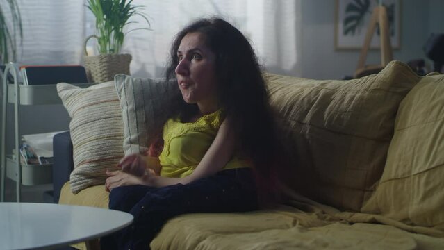 Couple talking nervously and arguing while woman with a disability sitting on a sofa and man walking around the room at home