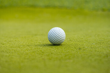 White golf ball on green fake grass.
