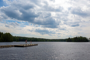 Wooden pier on the lake side. Partly cloudy summer day.