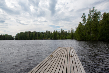 Wooden pier on the lake side. Partly cloudy summer day.