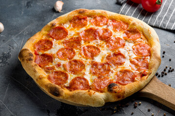 Pepperoni pizza on wooden board on grey table side view