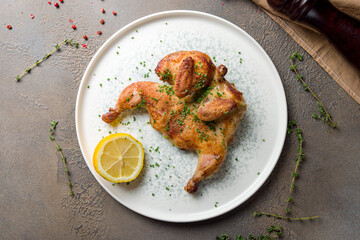 fried chicken tobacco with sliced green onion and lemon on plate top view