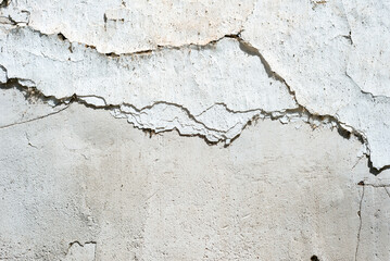 Concrete wall painted white with cracks on it