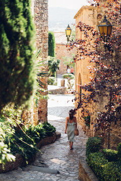 Chica paseando por antiguas calles de piedra y flores en Pals, provincia de Girona, Costa Brava