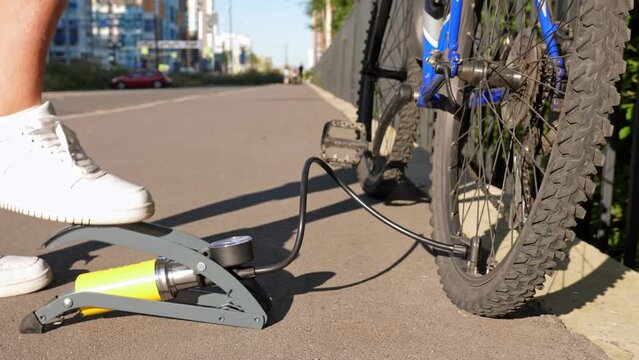 Man inflating bike tire outdoors. Pumping up bicycle tyre. Closeup