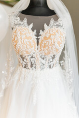 Amazing white wedding embroidered dress with tender floral patterns, long gorgeous bridal veil on black mannequin.