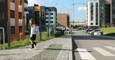 schoolgirl crosses the road at a pedestrian crossing