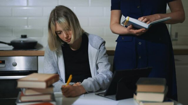 Teenage girl and her mother doing schoolwork at home.