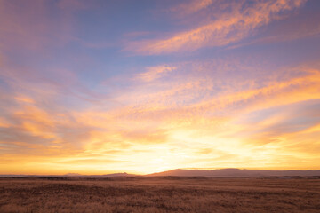 Colorful sunrise over distant mountains and dry plains