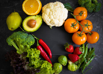 Different vegetables and fruits on a dark background