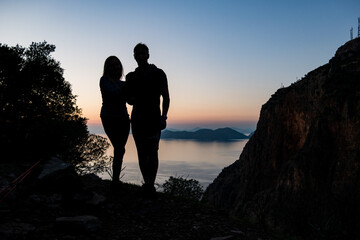 Silhouettes of a couple in love against the backdrop of mountains and the sea