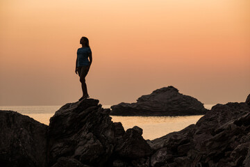 
Silhouette of a girl on a background of stone and sea