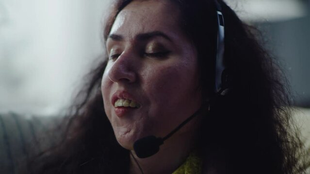 Close up shot of woman with a disability at home having online conversation via video call wearing headset while working remotely at home