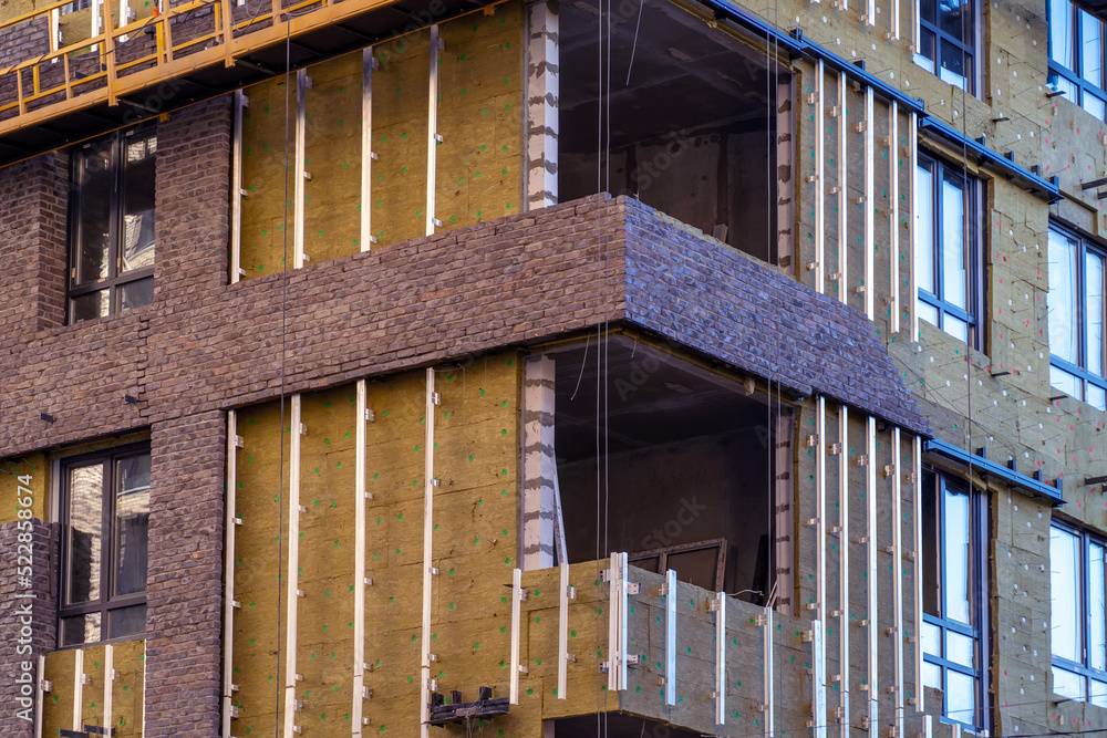 Poster monolithic concrete frame of apartment building under construction with partially attached facade cl