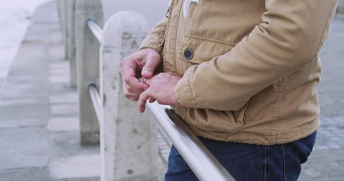 Thinking man touching wedding ring on finger while wishing, feeling sad and lonely outside by a sea or ocean. Depressed, frustrated or widower feeling regret, upset or worried over cheating or affair