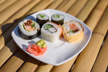 Appetizing sushi close-up. Maki and rolls with tuna, salmon, shrimp, crab and avocado. Top view of assorted sushi on a dish.