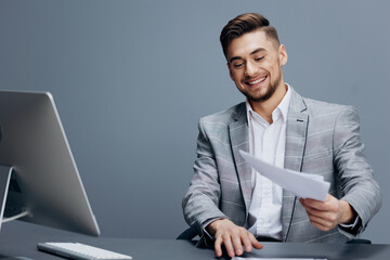 handsome man in a gray suit sits in front of a computer executive