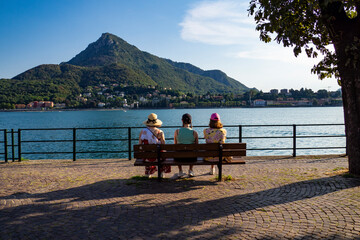 Tourists sitted on a bench on the lakeside of Lecco