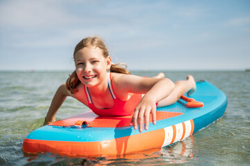 Happy teen girl lying on paddle board and enjoy water
