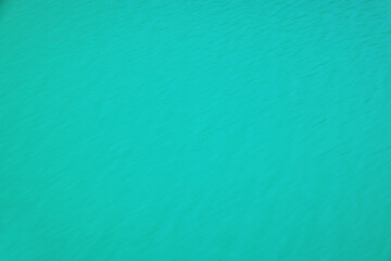 Meditative ripple of mountain lake. Beautiful relaxing background of blue green transparent water of glacial lake in sunlight. Sunny nature backdrop with clear water of glacier lake.