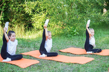 Children play sports in park using fitness mats. Training with gymnastics or aerobics