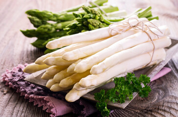 Fresh raw green and white asparagus bundle offered as close-up on wooden shabby chic tray