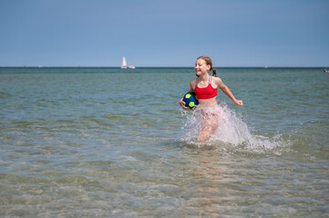 Beautiful child girl playful running in water at sea