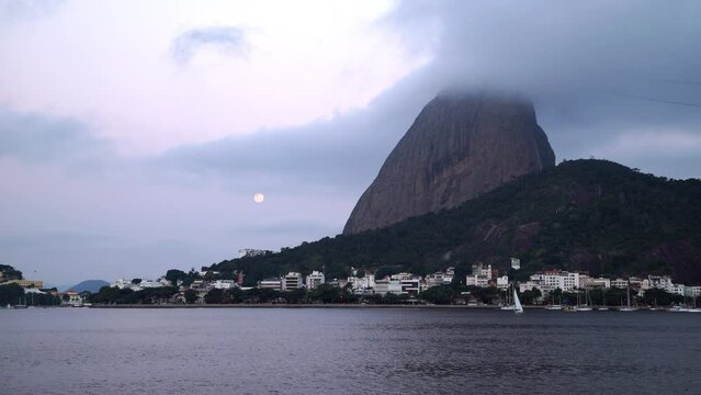 Lockdown Shot Of Nautical Vessels On Guanabara Bay By City With Moon In Cloudy Sky - Rio de Janeiro, Brazil