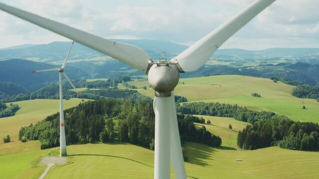Zoom out of camera from a propeller of the windmill in the field with mountains on the background.