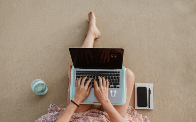 Crop self employed woman working on netbook on sandy seashore