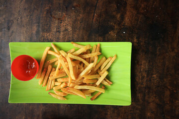 Fresh French fries in a bowl on old grunge dark textured wooden background
