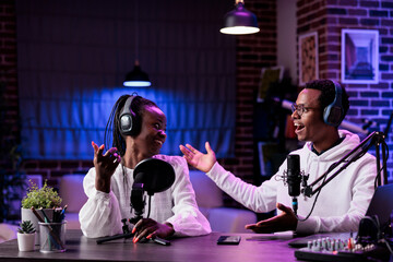 African american people chatting on podcast talk show, recording live content with sound equipment in studio. Man and woman broadcasting online discussion for channel audience. - obrazy, fototapety, plakaty