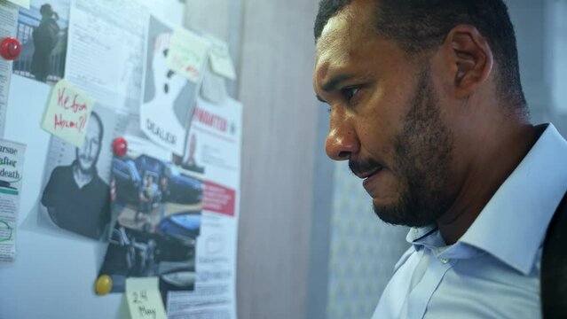 Focused investigator writing a line to the suspect on crime investigation board with red marker trying to find out who is a killer.High quality 4k footage