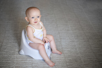 Cute baby in a diaper sitting on a potty. Toilet and potty training. A small child gets used to a useful skill. Hygiene.Baby sitting on a potty toilet stool potty.