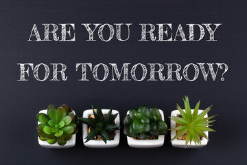 Text ARE YOU READY FOR TOMORROW? on black chalkboard with green plants. Business concept.