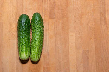 Two fresh green cucumbers lie on the left on the kitchen cutting board - the harvest is ripe, harvest, fresh green vegetables, growing vegetables, healthy lifestyle, healthy eating, cooking, ingredien