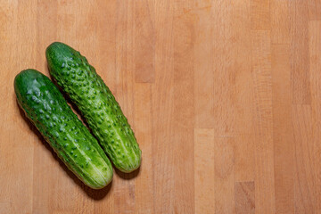 Two fresh green cucumbers lie on the left on the kitchen cutting board - the harvest is ripe, harvest, fresh green vegetables, growing vegetables, healthy lifestyle, healthy eating, cooking, ingredien