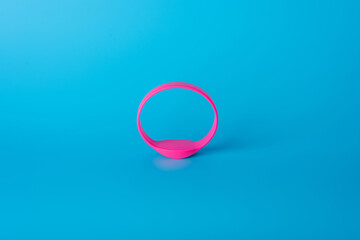Pink silicone bracelet on a blue background - an electronic locker key in the gym, fitness room,...