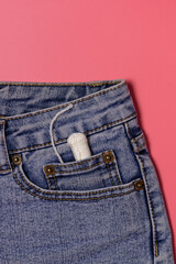 In the front pocket of denim shorts lies a female tampon, blue jeans, feminine hygiene, women's...