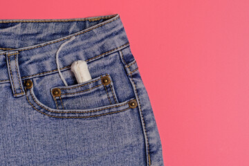 In the front pocket of denim shorts lies a female tampon, blue jeans, feminine hygiene, women's...