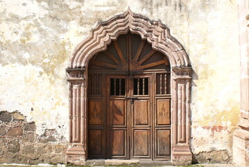 Fototapeta na wymiar Puerta de madera antigua en arco decorado