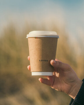 Hand Holding paper Coffee cup in warm tones photograph 