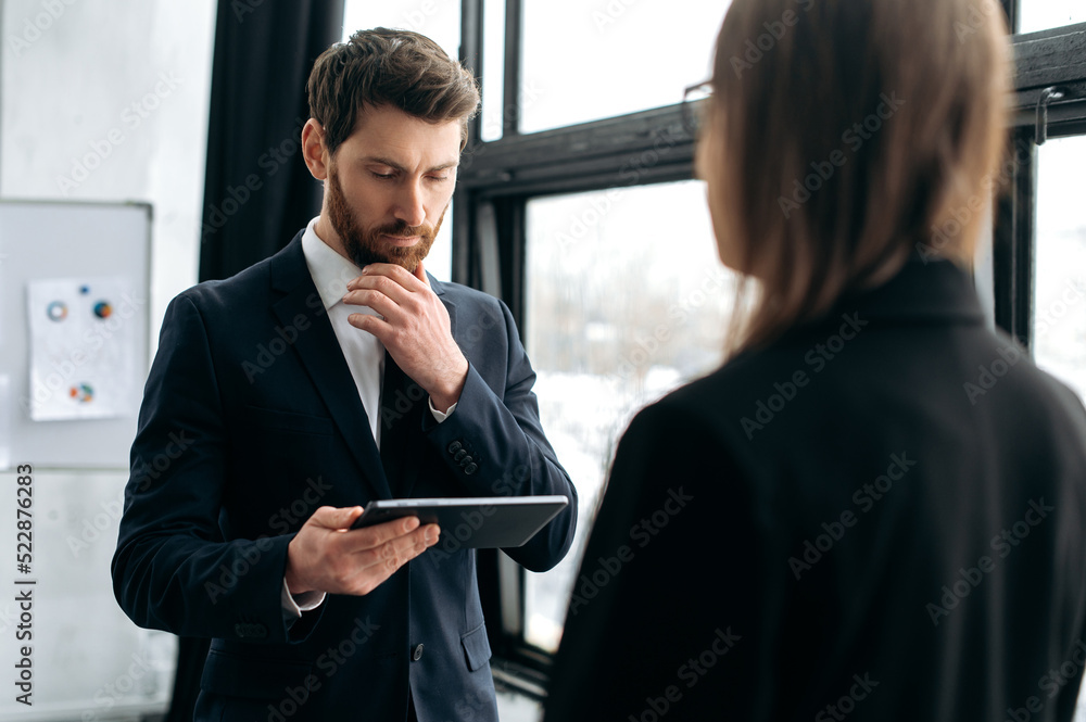 Wall mural two successful company colleagues, caucasian man in a formal suit, communicates with his female coll