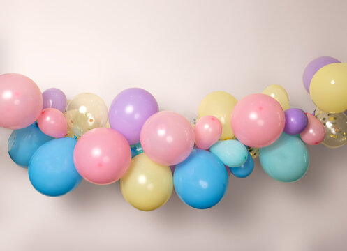 A close up image of a soft pastel balloon garland against a pink background