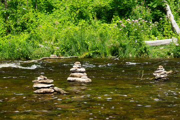 River with stream, plants and rock sculptures (Piles of stones) in sunny summer day