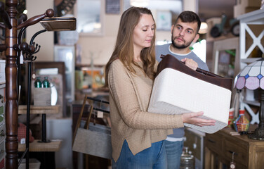 Attractive girl with boyfriend choosing home decor elements in furnishings store