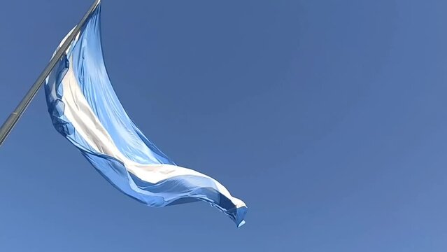 Bandera Argentina flameando con mucho viento y cielo azul