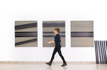 Woman artist assembling modern art installation on the art gallery wall